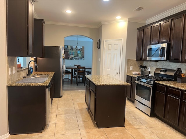 10022 Hyacinth Way, Conroe, TX 77385 - kitchen with appliances with stainless steel finishes, a kitchen island, dark brown cabinets, stone counters, and decorative backsplash