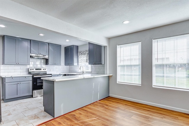 1316 Bailey St, Wharton, TX 77488 - kitchen with electric range, tasteful backsplash, a peninsula, light countertops, and baseboards
