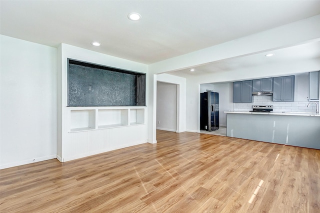 1316 Bailey St, Wharton, TX 77488 - kitchen with black fridge with ice dispenser, electric stove, under cabinet range hood, light wood-style flooring, and light countertops