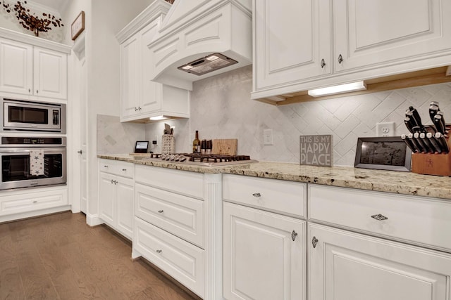 510 Blossom Cove Ct, Pinehurst, TX 77362 - kitchen with stainless steel appliances, white cabinets, custom exhaust hood, dark wood-style floors, and light stone countertops