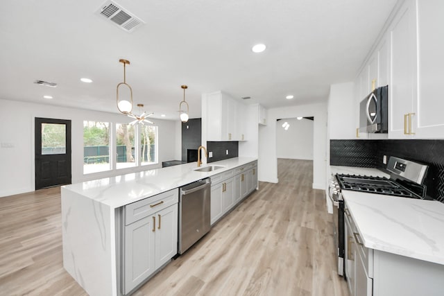 5638 N Braeswood Blvd, Houston, TX 77096 - kitchen featuring stainless steel appliances, a sink, a peninsula, light wood-style flooring, and light stone counters