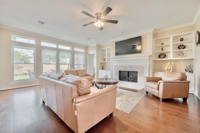 4106 Alice Dr, Sugar Land, TX 77478 - living area featuring built in shelves, a fireplace, dark wood finished floors, ceiling fan, and crown molding
