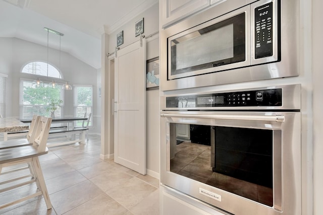 4106 Alice Dr, Sugar Land, TX 77478 - kitchen featuring appliances with stainless steel finishes, vaulted ceiling, baseboards, light tile patterned flooring, and white cabinets