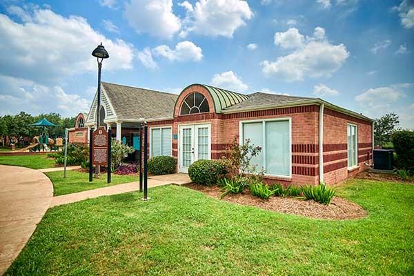 4106 Alice Dr, Sugar Land, TX 77478 - view of front facade featuring brick siding, french doors, a front yard, central air condition unit, and a playground