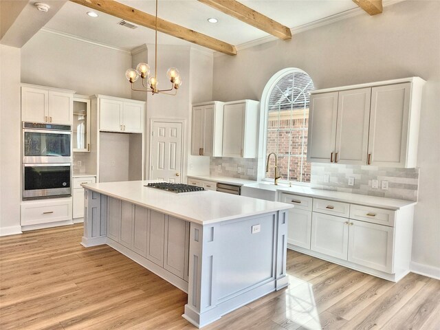 9923 Eden Valley Dr, Spring, TX 77379 - kitchen with a sink, appliances with stainless steel finishes, tasteful backsplash, white cabinetry, and beam ceiling