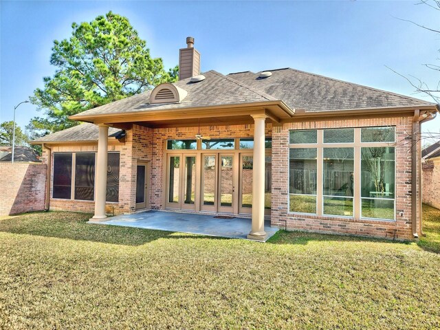 9923 Eden Valley Dr, Spring, TX 77379 - back of house with brick siding, a lawn, a chimney, a shingled roof, and a patio