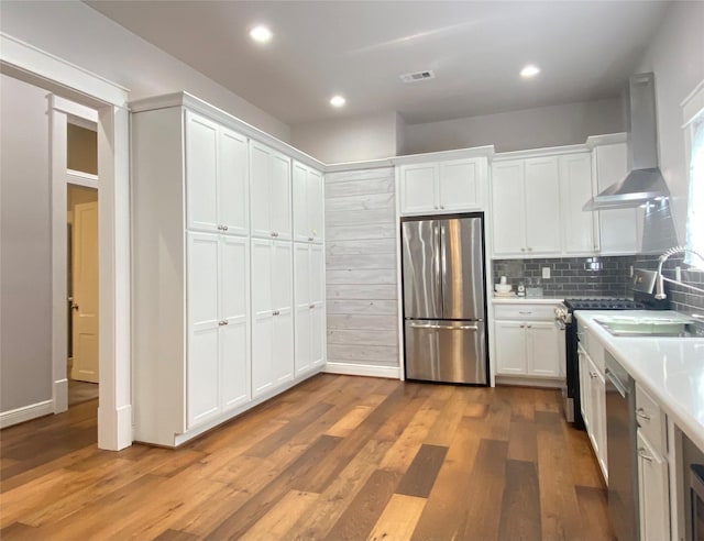 2012 Avenue N 1/2 Ave N 1/2, Galveston, TX 77550 - kitchen with stainless steel appliances, wall chimney exhaust hood, white cabinetry, light countertops, and wood finished floors