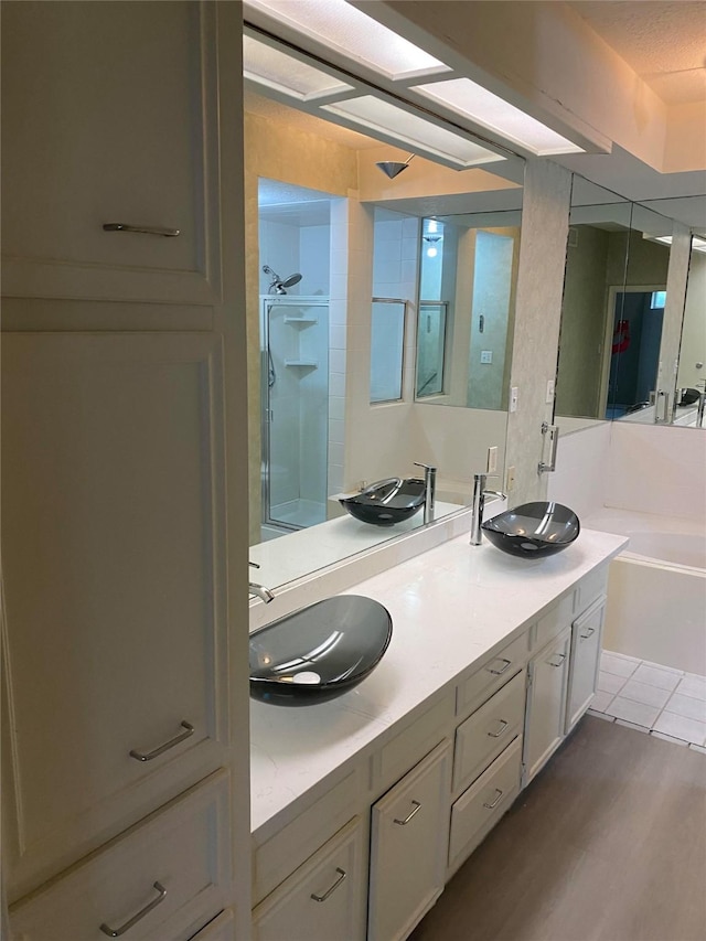 4315 Westheimer Rd, Houston, TX 77027 - bathroom featuring walk in shower, double vanity, wood finished floors, and a bath