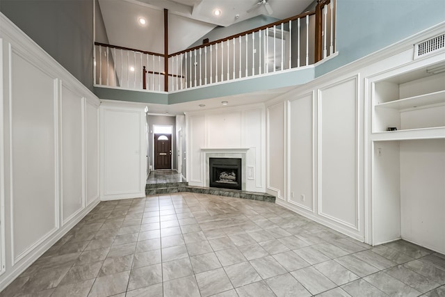4315 Westheimer Rd, Houston, TX 77027 - unfurnished living room featuring a decorative wall, high vaulted ceiling, and a fireplace with raised hearth