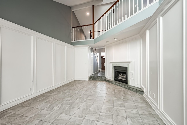4315 Westheimer Rd, Houston, TX 77027 - unfurnished living room with a decorative wall, high vaulted ceiling, light marble finish floors, a fireplace with raised hearth, and beam ceiling