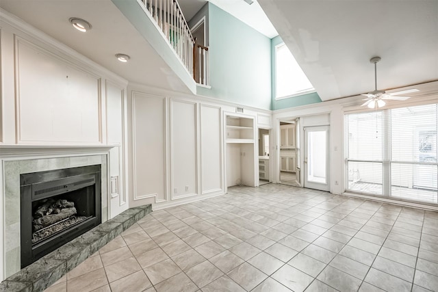 4315 Westheimer Rd, Houston, TX 77027 - unfurnished living room with a decorative wall, ceiling fan, a high end fireplace, a high ceiling, and light tile patterned floors