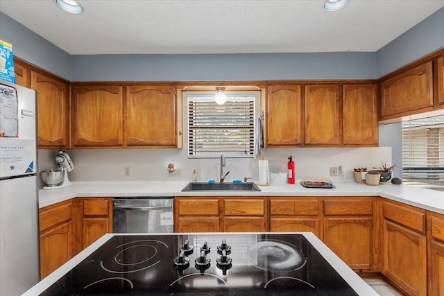 1520 Sycamore St, Navasota, TX 77868 - kitchen featuring dishwasher, a sink, freestanding refrigerator, and brown cabinets