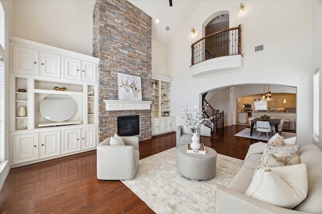 614 W Bell St Unit A, Houston, TX 77019 - living room featuring arched walkways, wood finished floors, high vaulted ceiling, a stone fireplace, and stairway