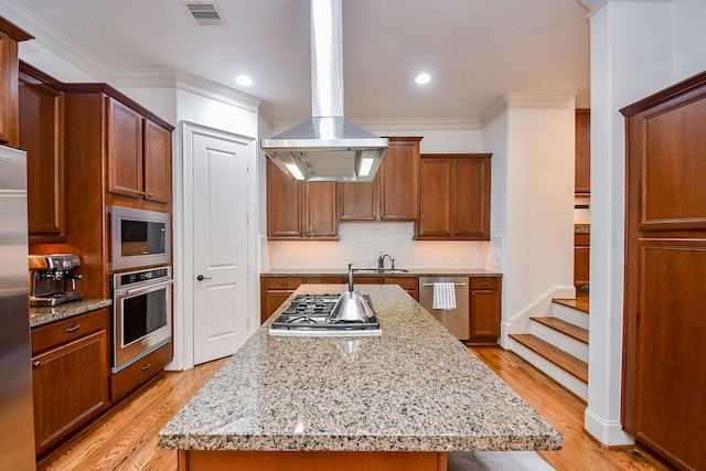 4006 Feagan St Unit D, Houston, TX 77007 - kitchen featuring appliances with stainless steel finishes, island range hood, decorative backsplash, a sink, and light wood-type flooring