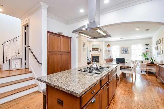 4006 Feagan St Unit D, Houston, TX 77007 - kitchen featuring island exhaust hood, stainless steel gas stovetop, brown cabinets, light wood-style flooring, and crown molding