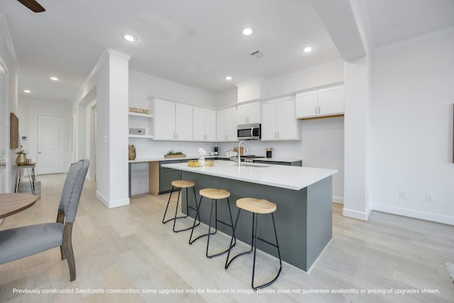222 E 27th St, Houston, TX 77008 - kitchen featuring stainless steel microwave, open shelves, light wood-style flooring, white cabinetry, and crown molding