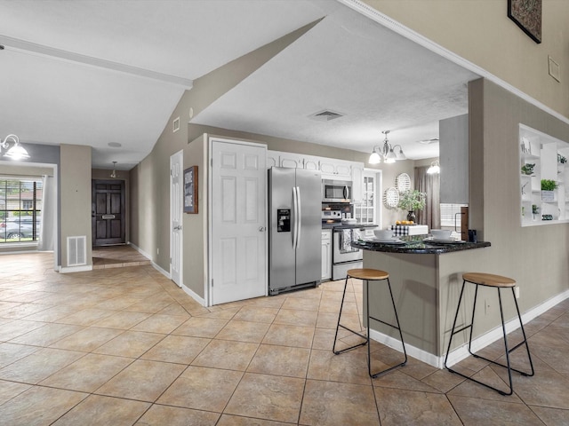 3309 Westbrook Cir, Pasadena, TX 77503 - kitchen featuring appliances with stainless steel finishes, a chandelier, a breakfast bar, a peninsula, and light tile patterned flooring