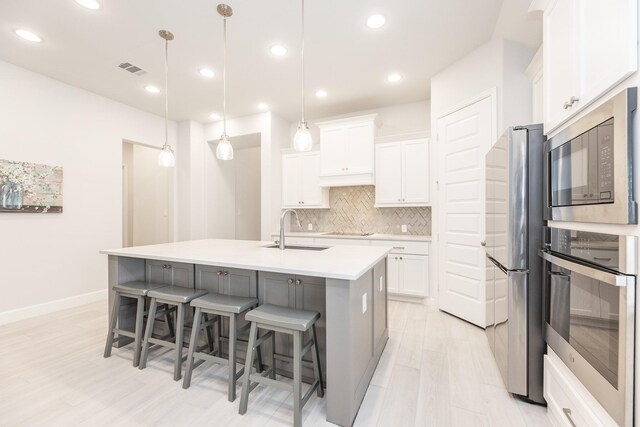29446 Pearwood Dr, Katy, TX 77494 - kitchen with stainless steel appliances, a sink, tasteful backsplash, white cabinetry, and a kitchen breakfast bar