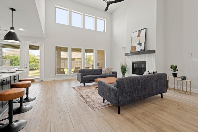 7314 Autumn Sage Dr, Katy, TX 77493 - living area featuring a tiled fireplace, light wood finished floors, baseboards, and a towering ceiling