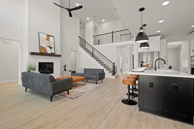 7314 Autumn Sage Dr, Katy, TX 77493 - living room with a glass covered fireplace, light wood-style flooring, a towering ceiling, recessed lighting, and stairs