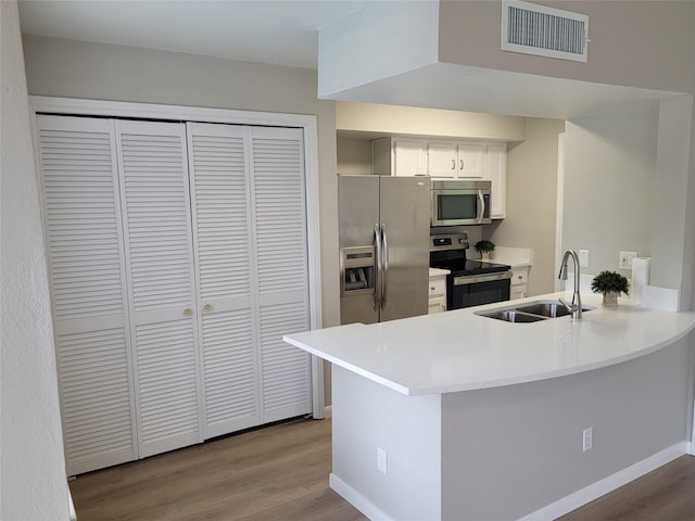 2300 Old Spanish Trl Unit 2136, Houston, TX 77054 - kitchen with appliances with stainless steel finishes, a sink, a peninsula, wood finished floors, and white cabinetry
