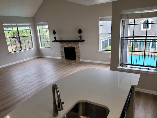 2300 Old Spanish Trl Unit 2136, Houston, TX 77054 - unfurnished living room with wood finished floors, baseboards, a stone fireplace, vaulted ceiling, and a sink