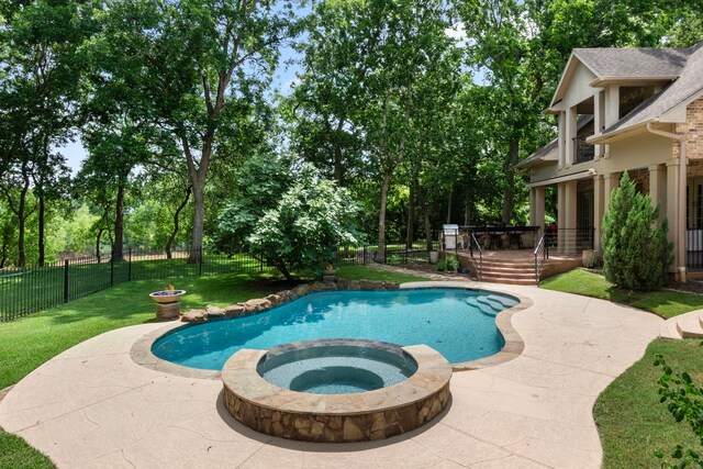 view of swimming pool with a pool with connected hot tub, a wooden deck, a patio, and view of wooded area