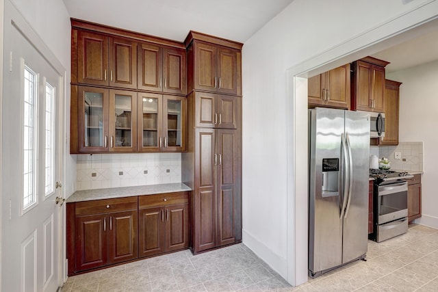 1016 Louise St, Houston, TX 77009 - kitchen featuring appliances with stainless steel finishes, backsplash, healthy amount of natural light, and glass insert cabinets