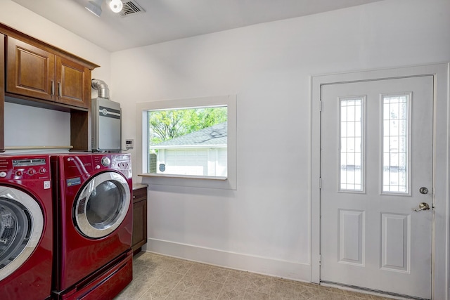 1016 Louise St, Houston, TX 77009 - laundry area featuring washer and clothes dryer, cabinet space, baseboards, water heater, and light tile patterned floors