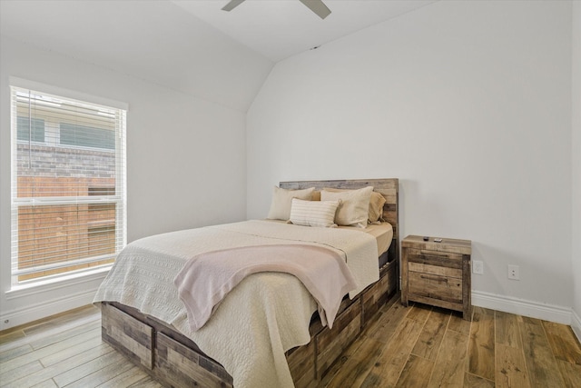 bedroom featuring wood finished floors, vaulted ceiling, baseboards, multiple windows, and a ceiling fan