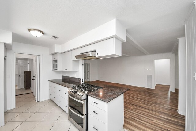 5103 Diamond Springs Dr, Missouri City, TX 77459 - kitchen with range with two ovens, white cabinets, a peninsula, under cabinet range hood, and dark stone counters