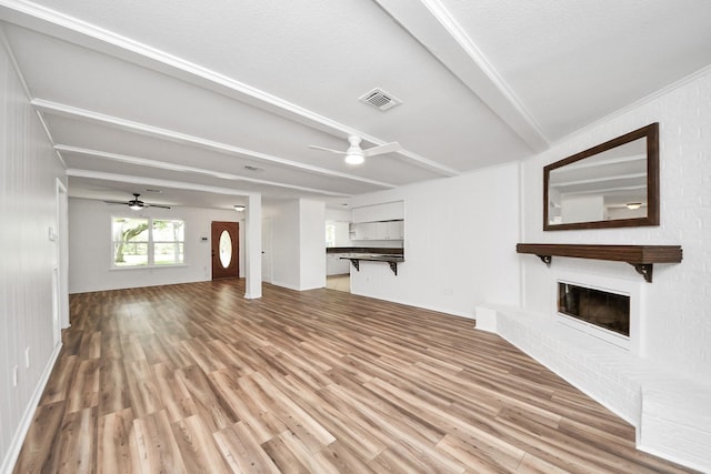 5103 Diamond Springs Dr, Missouri City, TX 77459 - unfurnished living room featuring a ceiling fan, light wood-type flooring, beamed ceiling, and a brick fireplace