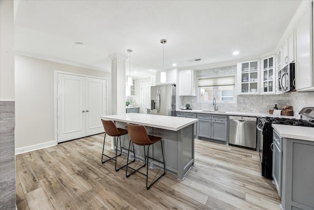 2514 Briarbrook Dr, Houston, TX 77042 - kitchen with appliances with stainless steel finishes, gray cabinetry, a kitchen bar, glass insert cabinets, and light countertops