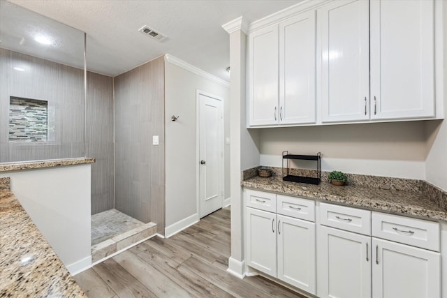 2514 Briarbrook Dr, Houston, TX 77042 - kitchen featuring light wood finished floors, white cabinets, crown molding, baseboards, and light stone countertops