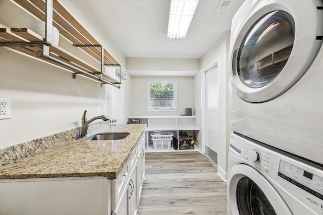 2514 Briarbrook Dr, Houston, TX 77042 - laundry room featuring estacked washer and dryer, cabinet space, and light wood-style floors
