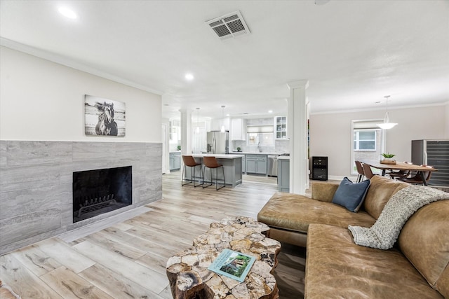 2514 Briarbrook Dr, Houston, TX 77042 - living room featuring light wood finished floors, ornamental molding, recessed lighting, a fireplace, and decorative columns