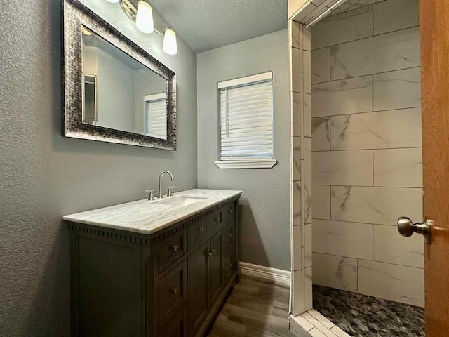207 Lucky Dr, Silsbee, TX 77656 - bathroom featuring wood finished floors, vanity, a tile shower, and baseboards