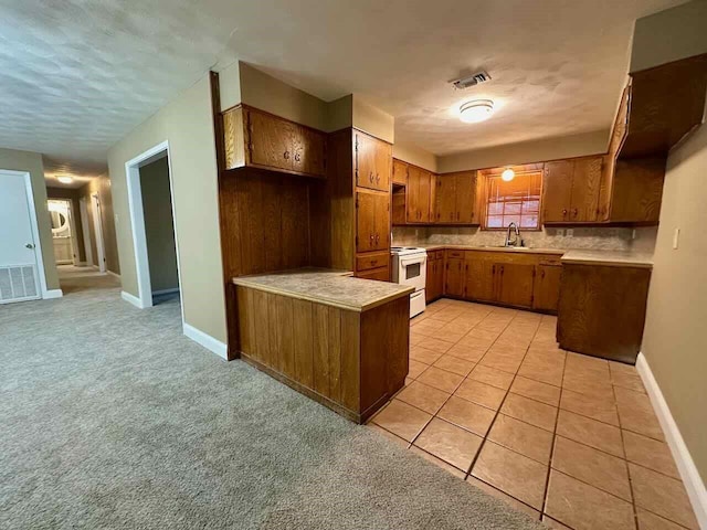 207 Lucky Dr, Silsbee, TX 77656 - kitchen with a peninsula, brown cabinets, light countertops, a sink, and baseboards