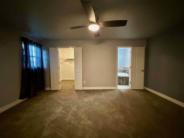 207 Lucky Dr, Silsbee, TX 77656 - unfurnished bedroom with a spacious closet, baseboards, dark carpet, a ceiling fan, and a closet