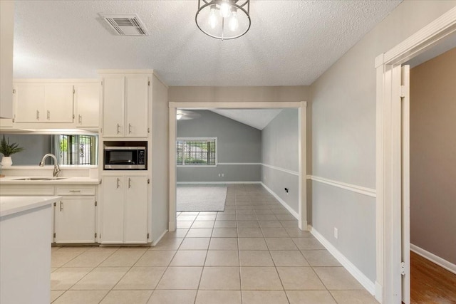 2003 Sieber Dr, Houston, TX 77017 - kitchen featuring stainless steel microwave, a sink, light countertops, a textured ceiling, and white cabinetry