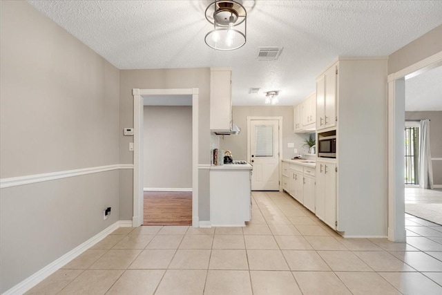 2003 Sieber Dr, Houston, TX 77017 - kitchen with a textured ceiling, light countertops, stainless steel microwave, light tile patterned floors, and white cabinetry