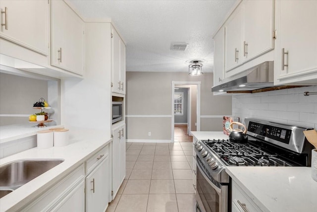 2003 Sieber Dr, Houston, TX 77017 - kitchen with stainless steel appliances, backsplash, white cabinets, light tile patterned floors, and a textured ceiling