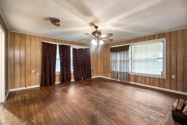 1306 Laurel St, La Marque, TX 77568 - empty room with hardwood / wood-style floors, ceiling fan, wooden walls, baseboards, and a textured ceiling
