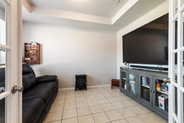 6303 Lemon Balm Ln, Crosby, TX 77532 - living room featuring light tile patterned floors, french doors, a tray ceiling, a wood stove, and baseboards