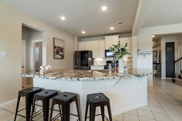 6303 Lemon Balm Ln, Crosby, TX 77532 - kitchen featuring black appliances, a kitchen breakfast bar, decorative backsplash, light tile patterned floors, and recessed lighting