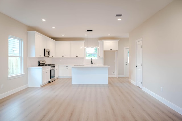 6322 Sayers St, Houston, TX 77026 - kitchen with appliances with stainless steel finishes, backsplash, light wood-type flooring, white cabinets, and recessed lighting