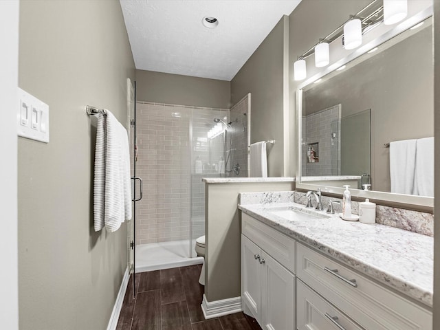 2815 Halton Ct, Kingwood, TX 77345 - bathroom with wood finished floors, a stall shower, baseboards, vanity, and toilet
