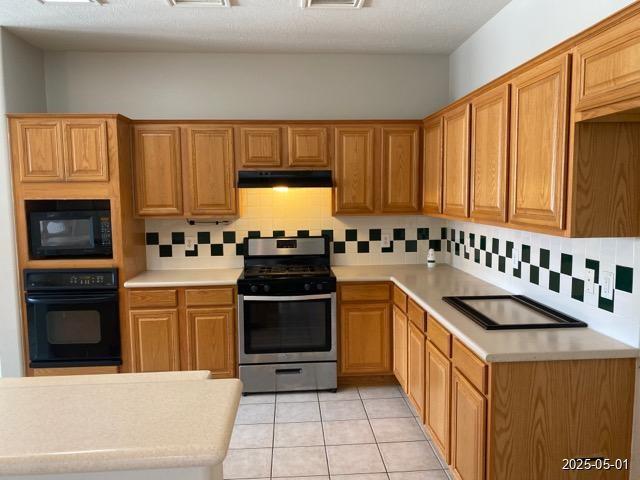 17523 Ginger Fields Ln, Tomball, TX 77377 - kitchen featuring black appliances, backsplash, light countertops, and under cabinet range hood