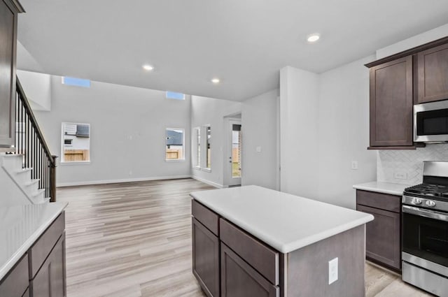 8802 Cecil Garden Ln, Cypress, TX 77433 - kitchen with stainless steel appliances, light countertops, backsplash, dark brown cabinetry, and light wood-style floors