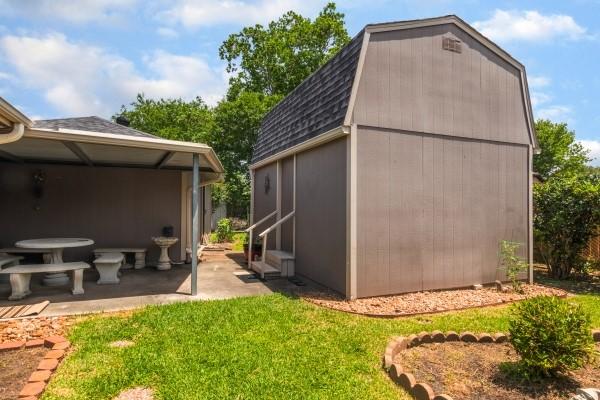 3314 Park Meadows Ave, Deer Park, TX 77536 - view of property exterior featuring a shingled roof, a yard, an outbuilding, a patio, and a gambrel roof